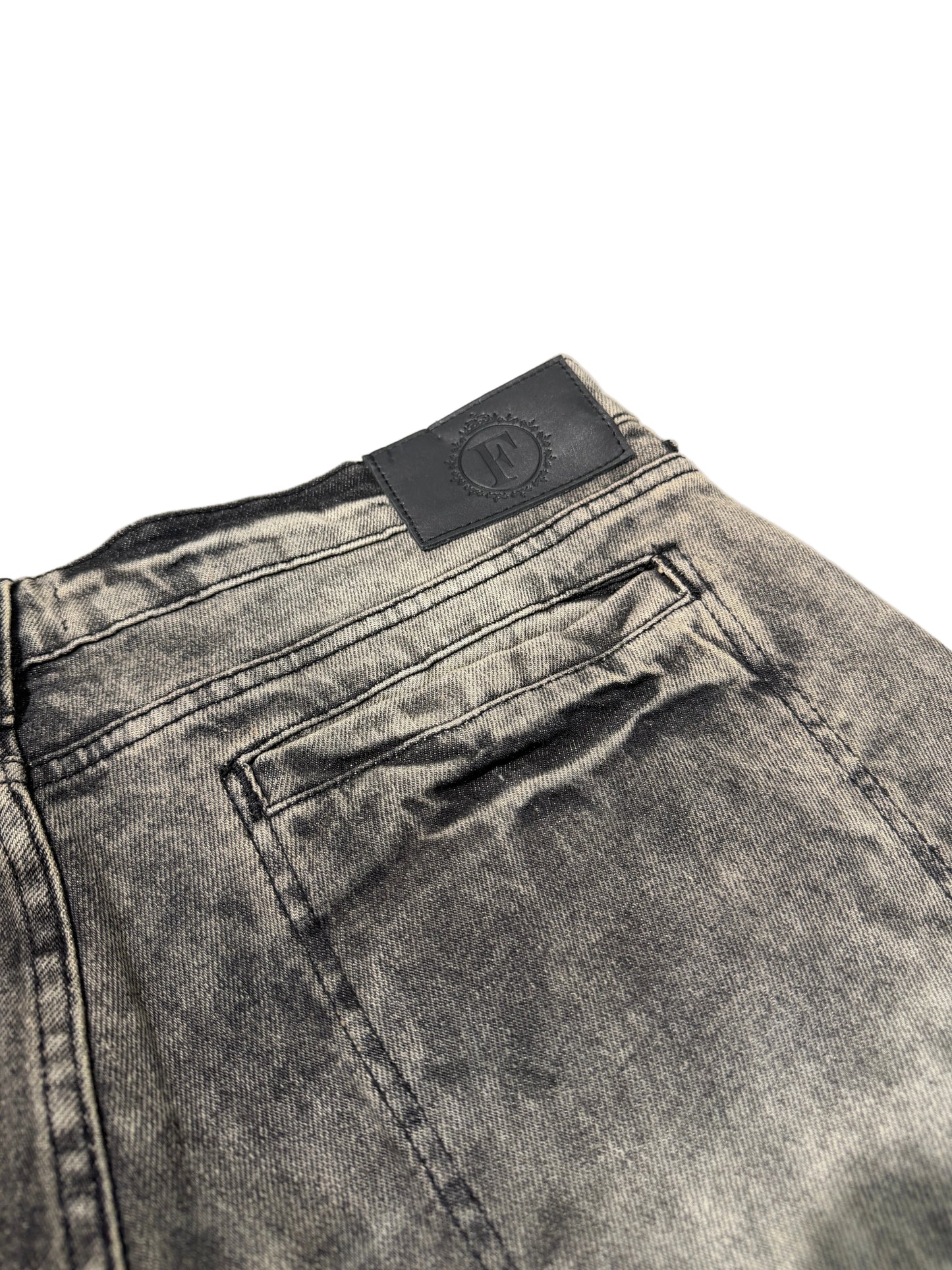 Close-up of a gray denim pocket with a brand label on a light gray background