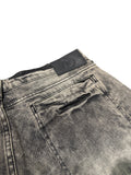Close-up of a gray denim pocket with a brand label on a light gray background